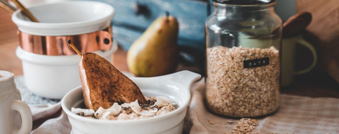 A cozy breakfast scene with a bowl of oats, sliced pear, and a rustic kitchen setting.