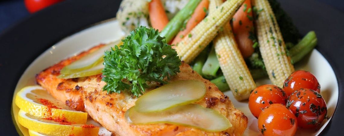 A beautifully plated salmon dish with fresh vegetables and lemon slices, perfect for a gourmet meal.